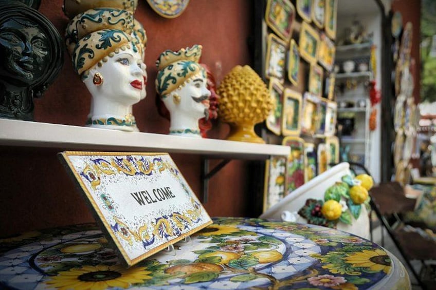 Een presentatie van keramische bustes en een 'WELCOME'-bord op een tafel met een bloemrijk tafelkleed. 2