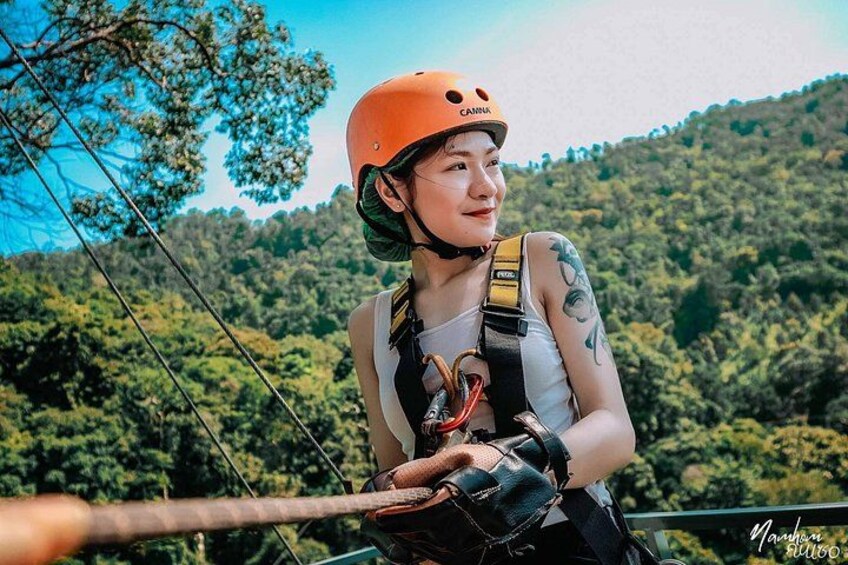 A person with a helmet and harness, preparing for an outdoor activity. 1