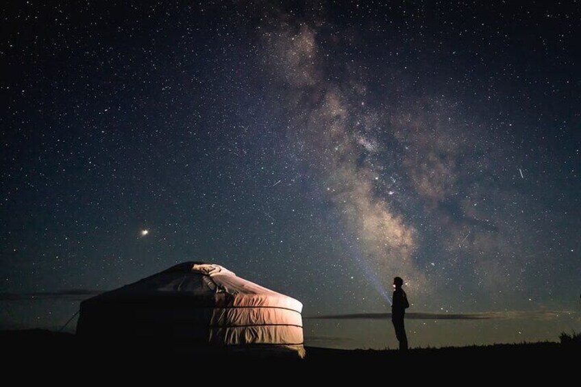 A person standing under a starry sky with a tent and the Milky Way visible. 5