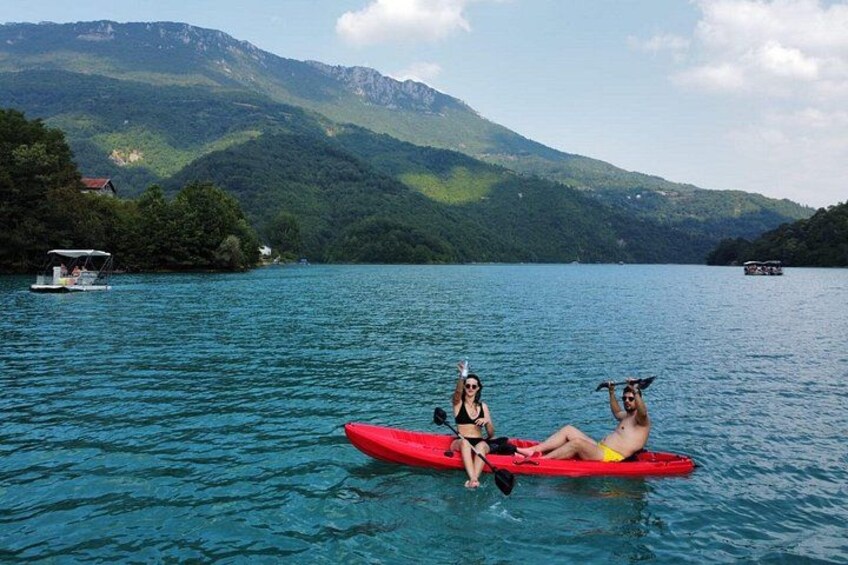 Dos personas kayakendo en un lago tranquilo con montañas al fondo. 3