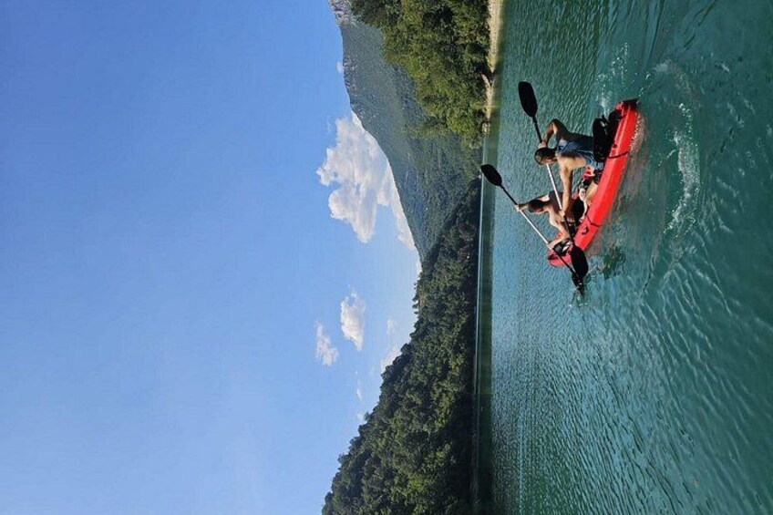 Un kayak rojo sobre aguas tranquilas, con una orilla boscosa y cielo despejado. 2