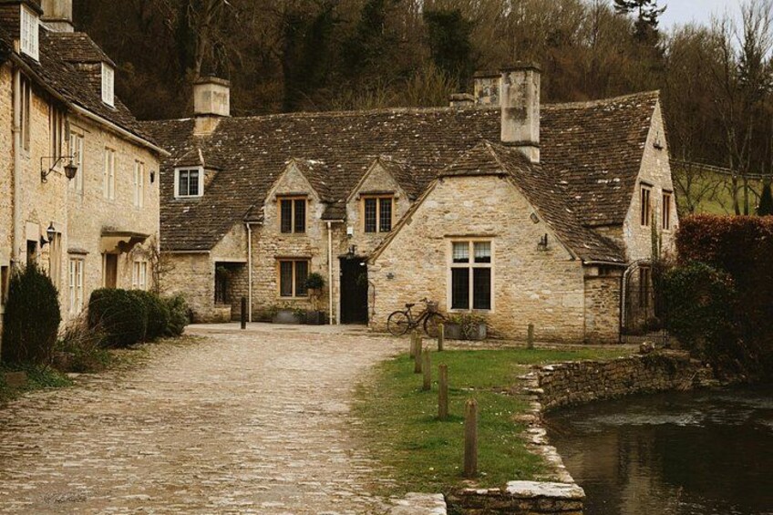A stone building with a cobblestone path leading to a water body. 4