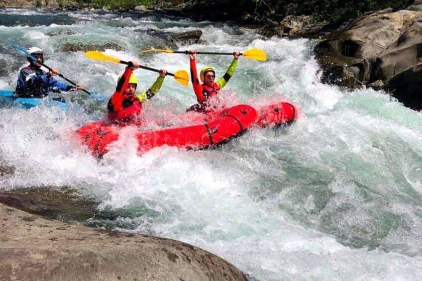 Actividad de rafting en aguas bravas con participantes en kayaks rojos y azules navegando rápidos. 4