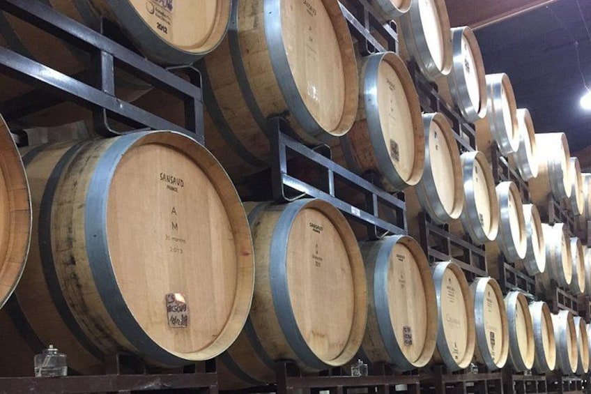 Wooden barrels stacked on metal shelves in a warehouse. 2