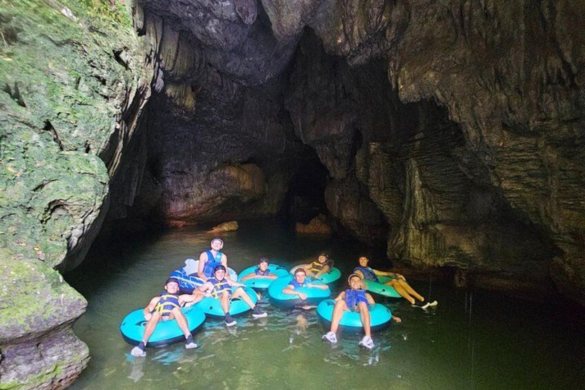 Menschen in blauen Luftmatratzen treiben in einem schmalen Wasserkanal in einer felsigen Höhle. 3