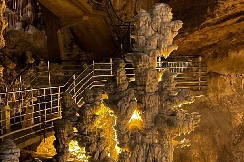A cave with stalactites, a metal staircase, and a railing. 3