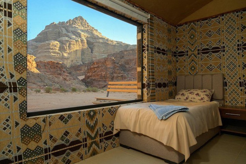 Un dormitorio con cama, ventana con vistas a la montaña y papel tapiz estampado. 1