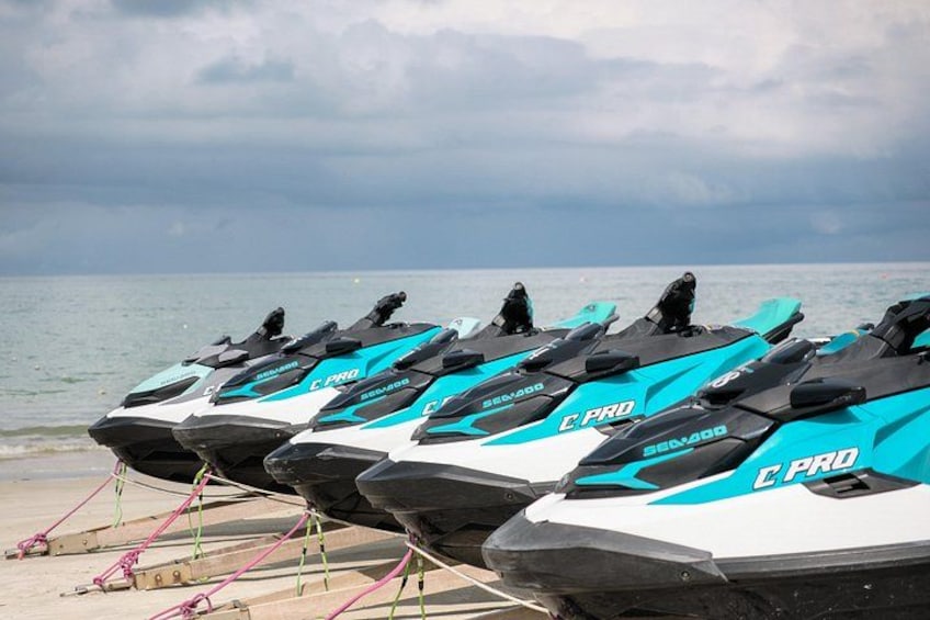 A row of jet skis on a beach with a cloudy sky in the background. 3