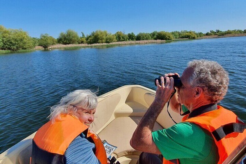 Two people in a boat on a river, wearing life jackets. 4