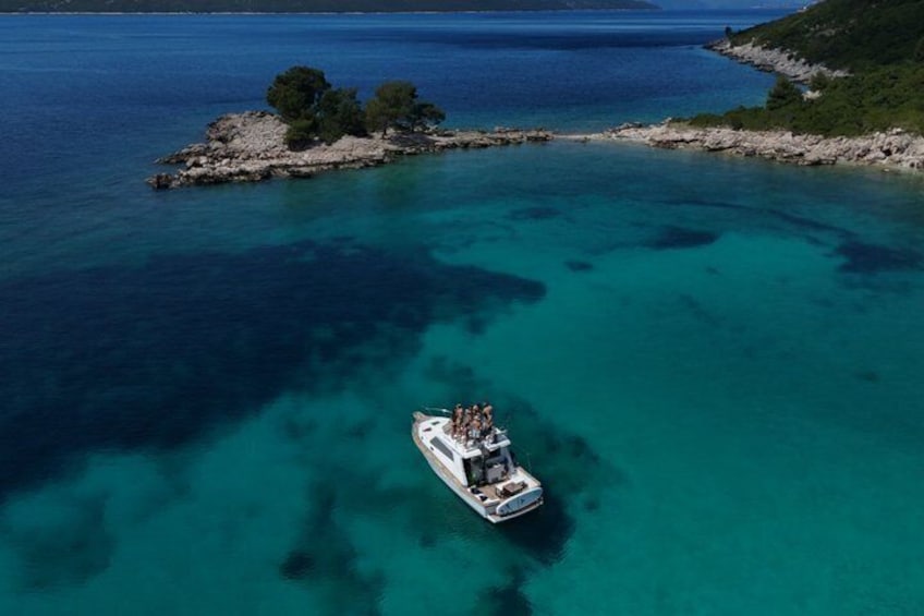 A boat on turquoise waters near a rocky island with trees. 3