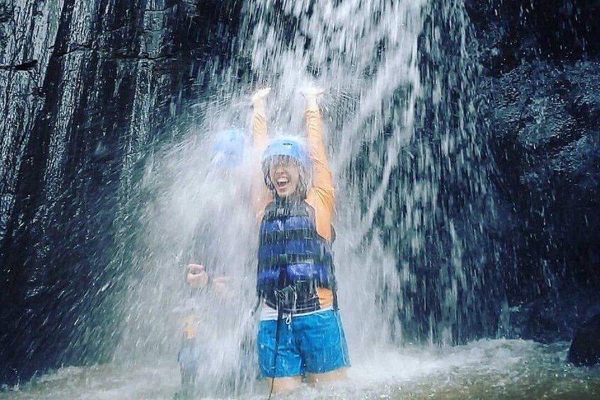 Una persona con salvagente blu e pantaloncini in piedi davanti a una cascata. 4