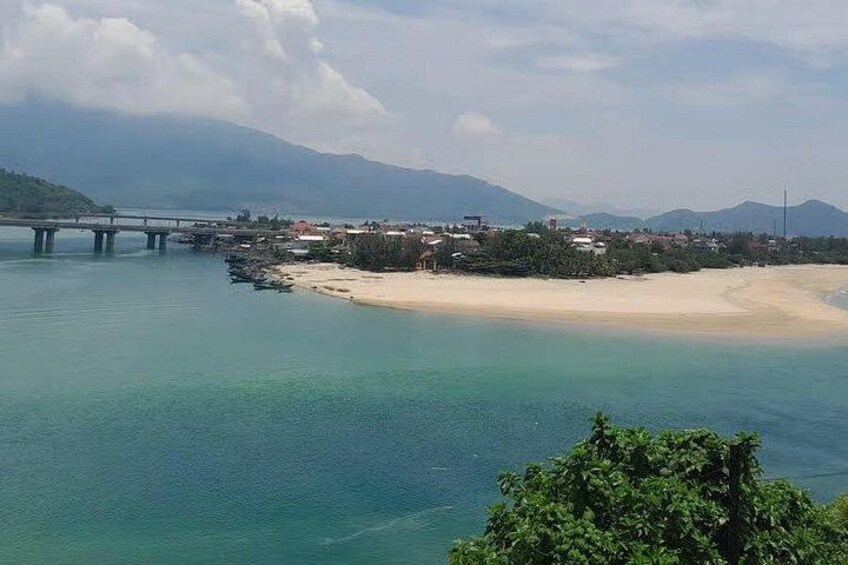 A coastal landscape with a bridge, beach, and mountains in the background. 5