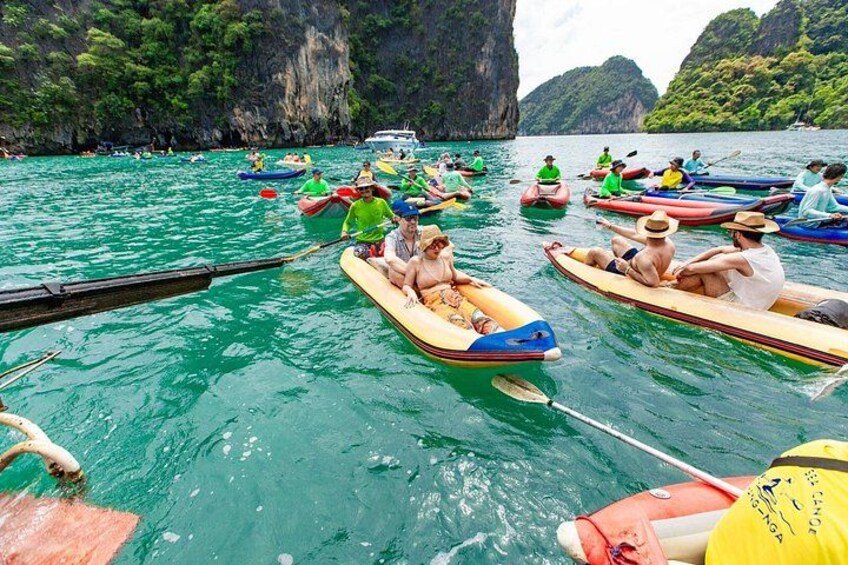 People in small boats on a turquoise sea with rocky cliffs in the background. 1