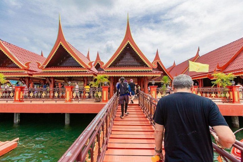A traditional Thai bridge with ornate architecture, leading to a building with a red roof. 5