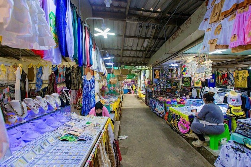A bustling indoor market with various stalls selling textiles, jewelry, and clothing. 4