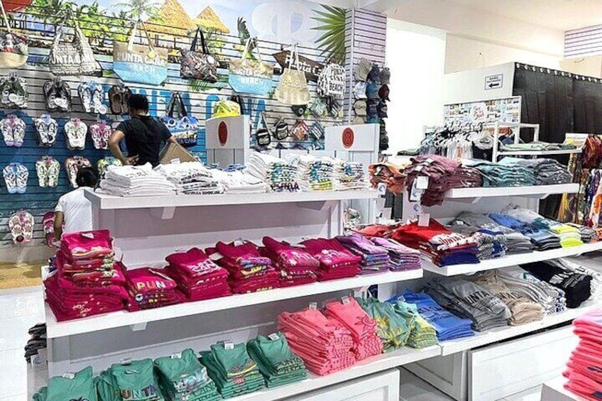 Un magasin de vêtements avec des étagères remplies de vêtements pliés et un présentoir de sacs. 2