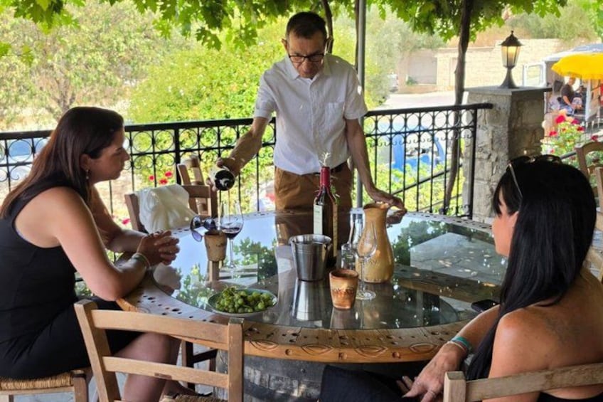 Un grupo de personas cenando en una mesa al aire libre mientras un camarero les atiende. 4