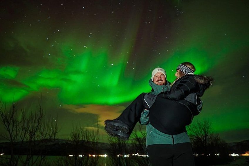 Deux personnes s’embrassent sous un ciel nocturne illuminé par des aurores boréales vertes. 4