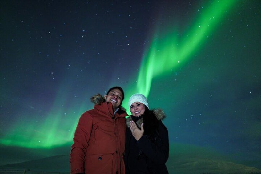 To personer står under en nattehimmel med grøn nordlys. 4