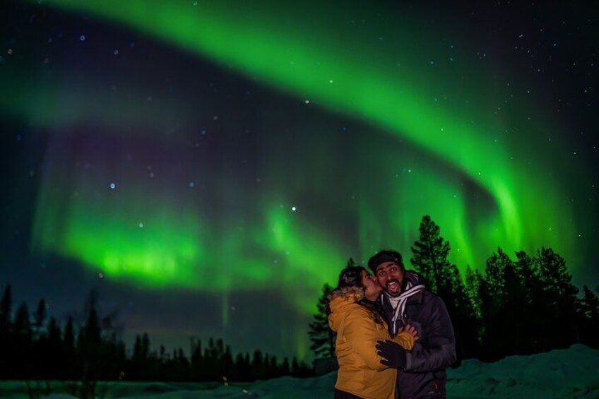Et par omfavner under nordlyset i et snølandskab. 5