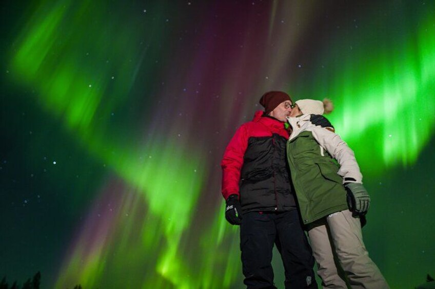 To personer omfavner under en nattehimmel med grønne nordlys. 2