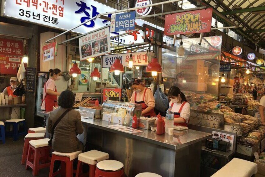 A bustling street food stall with multiple vendors and customers. 4