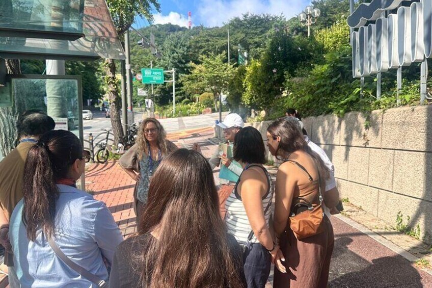 A group of people standing on a sidewalk near a bus stop. 2