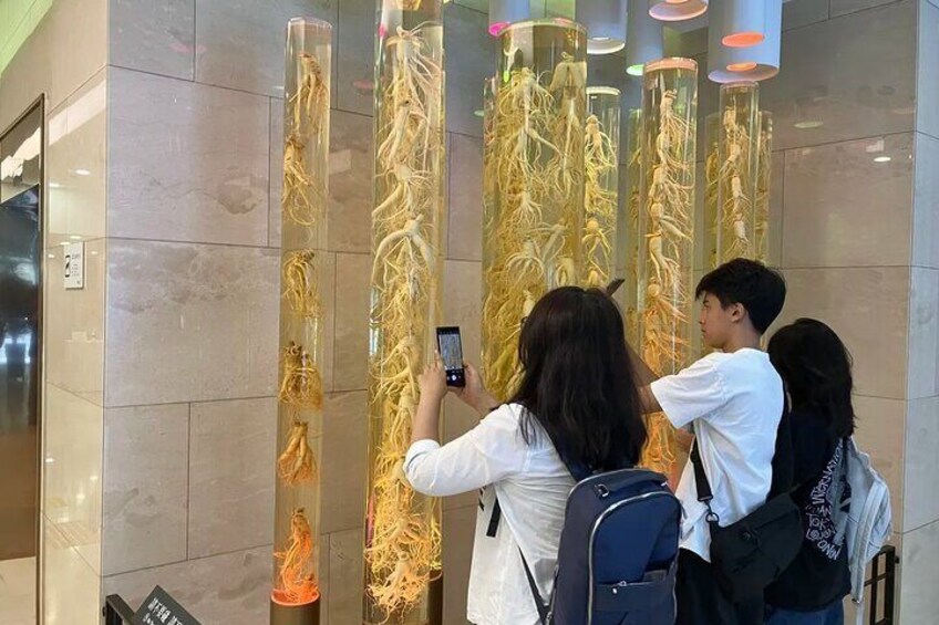 A group of people taking photos of a vertical display of golden roots in a modern building. 5