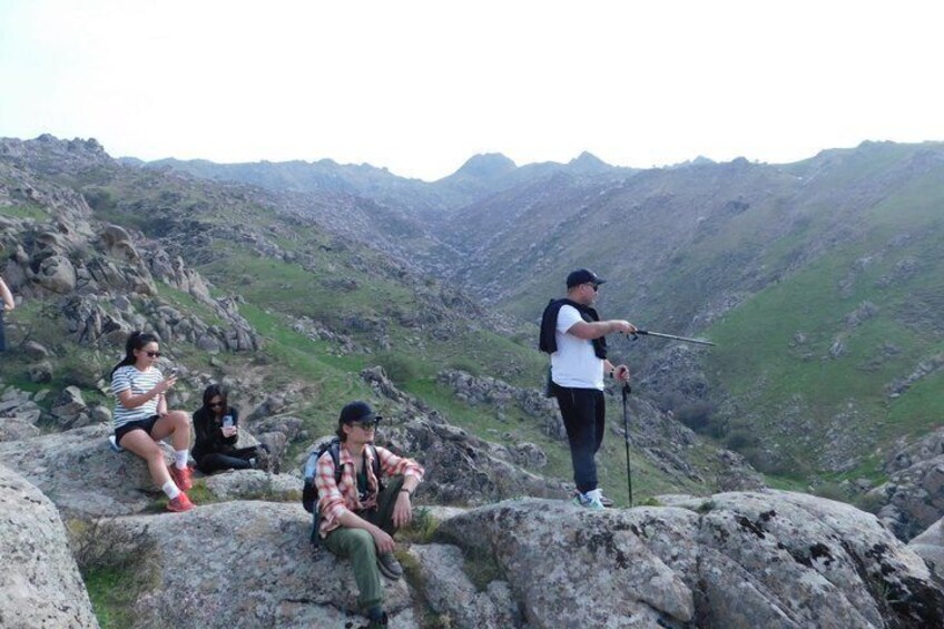 A group of people on a rocky mountain peak with a hiker aiming a bow. 3
