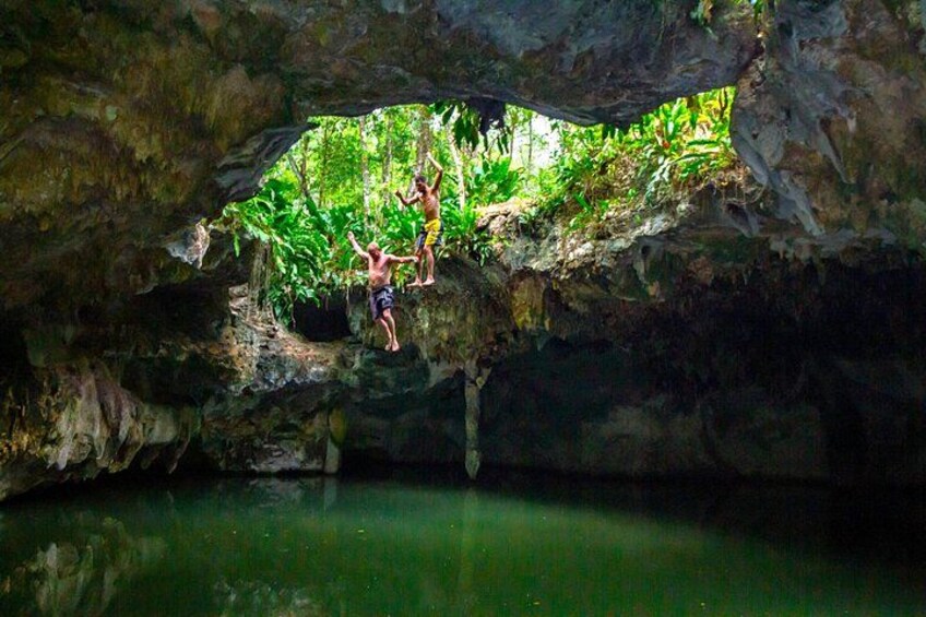 Two people climbing a rocky overhang with a body of water below. 3