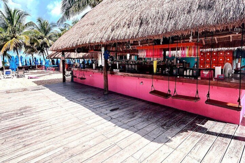 Un bar sulla spiaggia con tetto di paglia, veranda in legno e palme sullo sfondo. 3