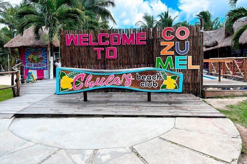 Un cartello di legno con la scritta 'Welcome to Cozumel' e 'Chula's Beach Club'. 2