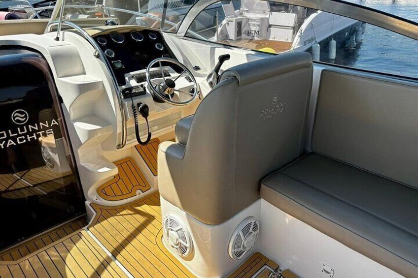 Interior de un barco con timón, panel de control y zona de estar. 4