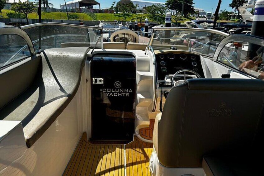 Interior de barco con cubierta de madera, timón y panel de control que dice 'Columbia Yachts'. 3