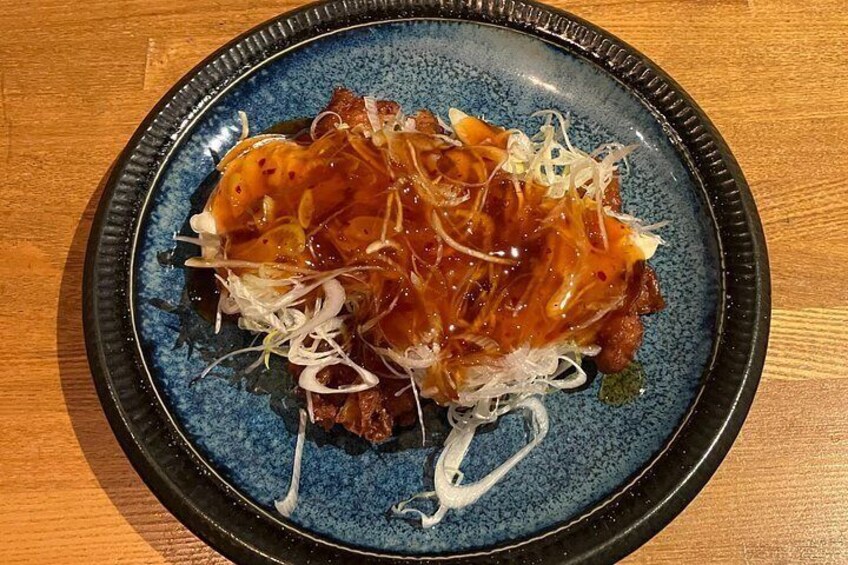 A blue plate with a dish topped with sauce and shredded white vegetables. 5