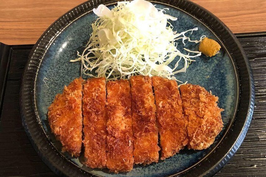 A plate with breaded cutlet, shredded cabbage, and a small mound of sauce. 3