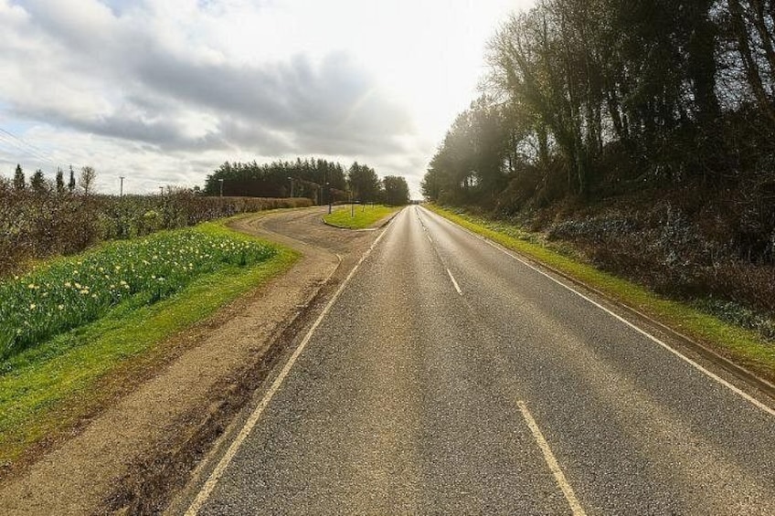 A rural road with a curve, bordered by fields and trees. 2