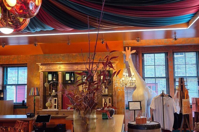A bar with a giraffe statue, a chandelier, and a plant arrangement. 5