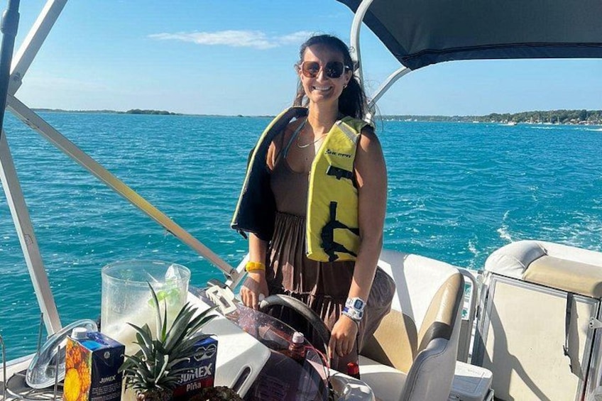 A person on a boat with a life jacket, steering wheel, and a drink on the table. 5