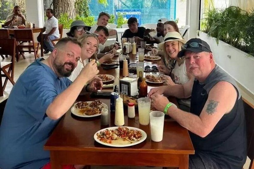 A group of people dining at a restaurant with various dishes and drinks on the table. 4