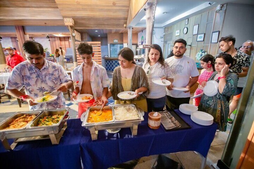 A buffet with various food items and people serving themselves. 4