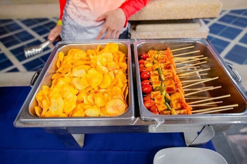 A buffet table with trays of chips and skewers of vegetables. 5