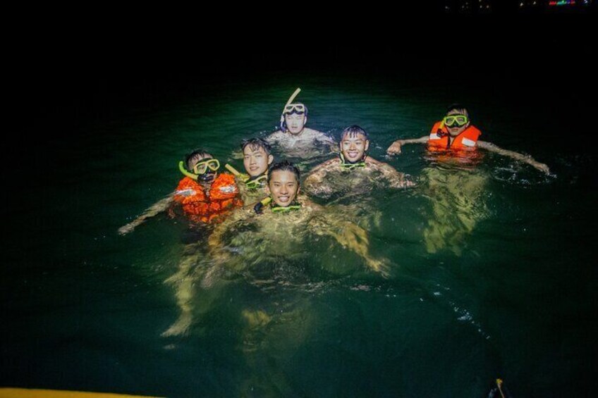 A group of people snorkeling in a body of water at night. 2