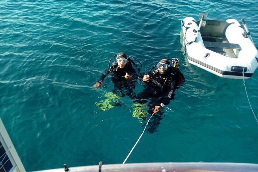 Two scuba divers in the water with a small boat nearby. 1