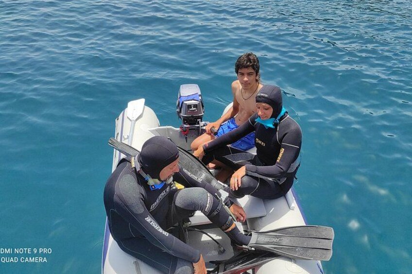Three people on a boat, one wearing a wetsuit and the other two in diving gear. 3