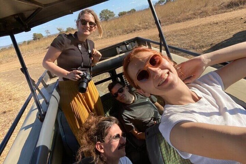 A group of people in a vehicle with a camera, a field, and a clear sky. 3