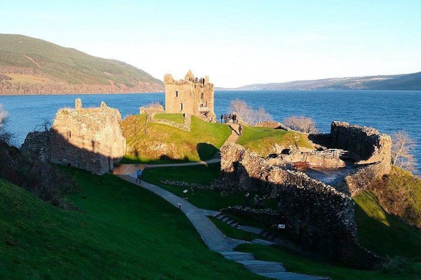 A historic castle ruin by a lake with a clear sky. 4