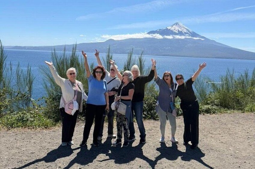 A group of people standing by a lake with a mountain in the background. 3