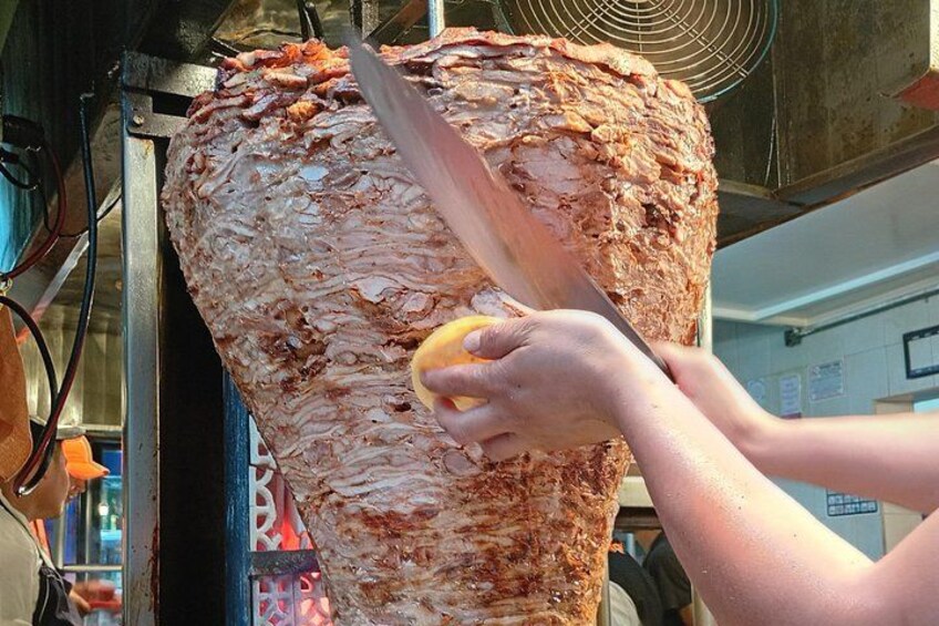 Una persona cortando carne de un asador vertical. 4