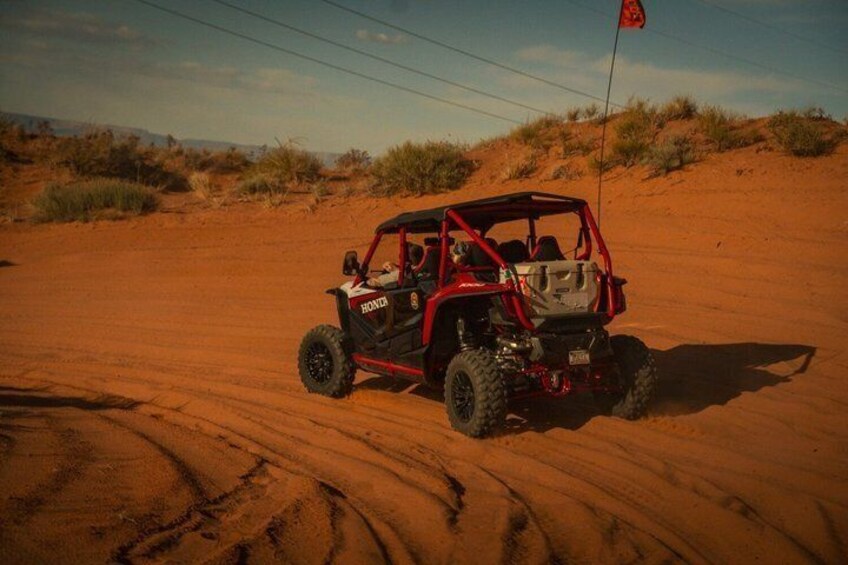 A red off-road vehicle on a sandy terrain with sparse vegetation. 3
